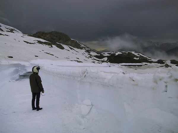 Motorcycle rider, walls of snow, dark sky