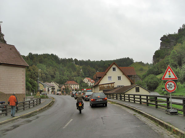 Motorcycle riders passing a row of cars