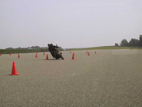 Motorcycle rider with passenger, riding around cones