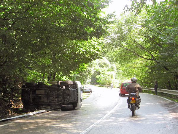 Car on its side, motorcycle rider