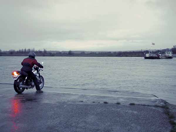 Motorcycle stopped just at the rim of a canal.