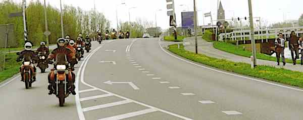 About twenty motorcycle riders in staggered formation