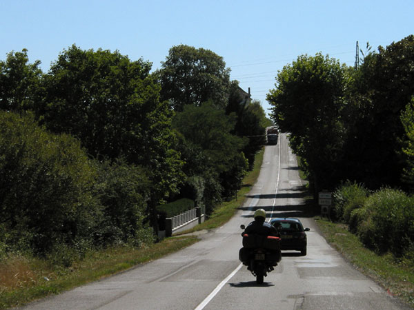 Motorcycle rider behind a car; oncoming truck