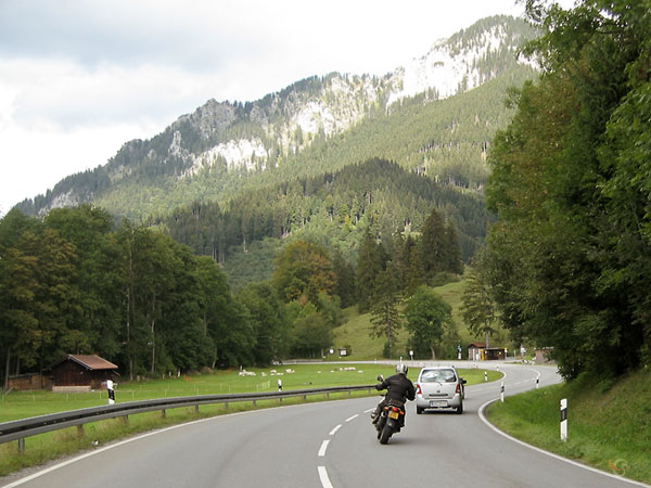 Motorcycle rider bahind a car on a beautiful road