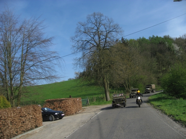 Motorcycle rider rides along line of classical cars, car drives from driveway