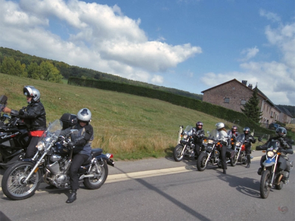 Stopped motorcycle riders; one is looking in the mirrors, another one is talking