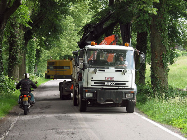 Motorcycle passing a truck and a crane, who block all view